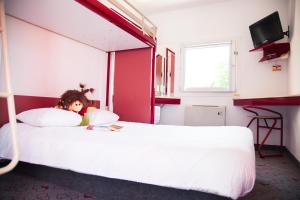 a doll laying on a bed in a bedroom at Class'Eco Namur in Namur