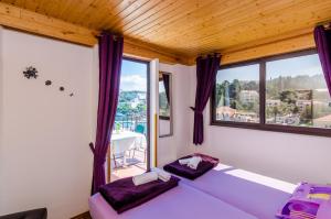 ein Zimmer mit einem Bett mit lila Kissen und Fenstern in der Unterkunft Apartments & Rooms Mihajica in Cavtat + 37 Fotos
