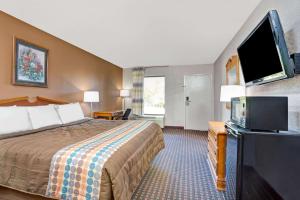 a hotel room with a bed and a flat screen tv at Days Inn by Wyndham Hernando in Hernando