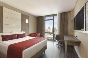 Habitación de hotel con cama, escritorio y TV. en Ramada Encore Istanbul Bayrampasa en Estambul