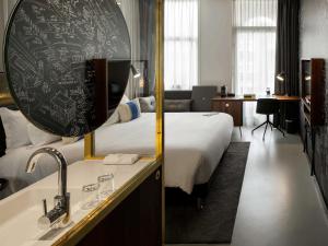 - une chambre d'hôtel avec un lit et une baignoire dans l'établissement INK Hotel Amsterdam - MGallery, à Amsterdam