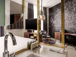 
a living room with a large mirror and a television at INK Hotel Amsterdam - MGallery in Amsterdam
