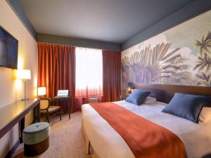 ボルドーにあるメルキュール シャトー シャルトロンの大きなベッドとデスクが備わるホテルルームです。