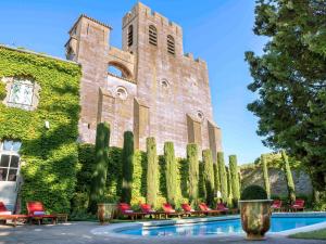 - un grand bâtiment en briques avec une piscine en face dans l'établissement Hotel de la Cité & Spa MGallery, à Carcassonne