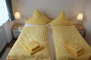 una camera con 2 letti con lenzuola e cuscini gialli di Haus Anker a Neuharlingersiel