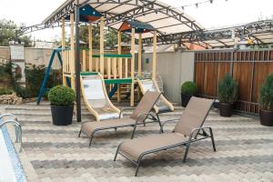 un parque infantil con 2 sillas y un columpio en Guest House Venezia, en Anapa