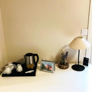 a table with a lamp a tea kettle and a picture at Le Clos Fleuri - Maison Vigier in Maringues