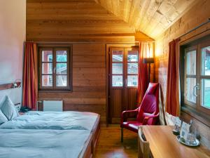 ein Schlafzimmer mit einem Bett und einem roten Stuhl in der Unterkunft Boutique Hotel Glocke in Reckingen - Gluringen