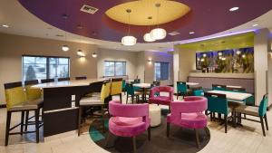 um restaurante com mesas e cadeiras cor-de-rosa e roxo em Best Western Plus Prien Lake Hotel & Suites - Lake Charles em Lake Charles