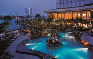 a hotel pool with palm trees and a building at Shangri-La Bangkok in Bangkok