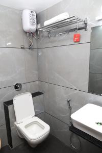 a bathroom with a toilet and a sink and a phone at Hotel Sai Neel in Surat