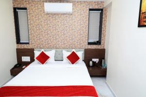 a bedroom with a white bed with red pillows at Hotel Sai Neel in Surat