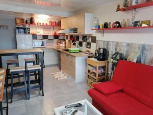 a living room with a red couch and a kitchen at Chambres d'Hôtes de l'Avison in Bruyères