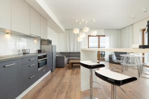 a kitchen and living room with white cabinets and black stools at Apartament nad morzem Słońce i Plaża in Dziwnówek
