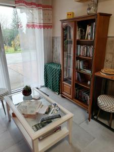 una sala de estar con una mesa y un estante de libros en Chambres d'Hôtes de l'Avison, en Bruyères
