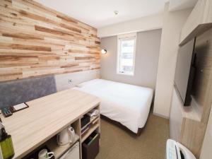 a small bedroom with a bed and a wooden wall at Super Hotel Shinagawa Aomono-Yokocho in Tokyo