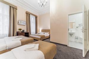 ベルリンにあるアッパー ルーム ホテル クアフュルステンダムのベッド3台とバスルームが備わるホテルルームです。