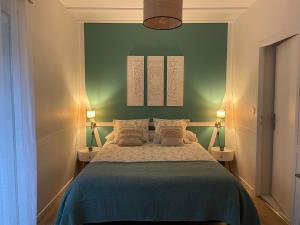 um quarto com uma cama com 2 candeeiros e uma parede verde em Maison Blanche em Lanton