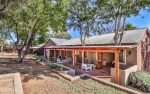 una casa de ladrillo con porche y patio en Rocky Hollow Lodge, en Pretoria