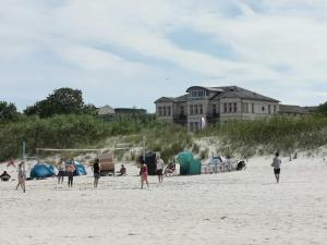 un groupe de personnes sur une plage avec un bâtiment en arrière-plan dans l'établissement Villa Anna Meerblick erste Reihe, à Ahlbeck