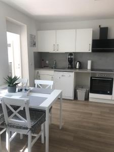 eine Küche mit weißen Schränken sowie einem Tisch und Stühlen in der Unterkunft Ferienwohnung M1 in Husby