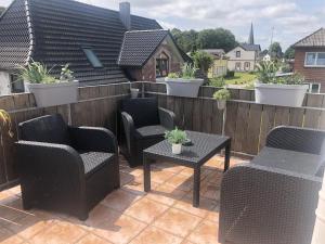 eine Terrasse mit Stühlen, Tischen und einem Zaun in der Unterkunft Ferienwohnung M1 in Husby
