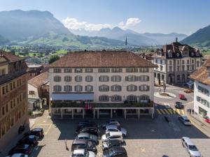 un gran edificio con coches estacionados en un estacionamiento en Wysses Rössli Swiss Quality Hotel, en Schwyz