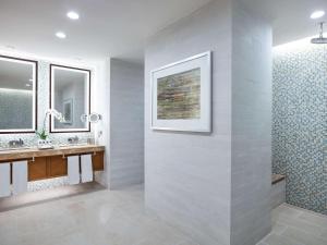 a bathroom with two sinks and two mirrors at Swissôtel Al Ghurair Dubai in Dubai