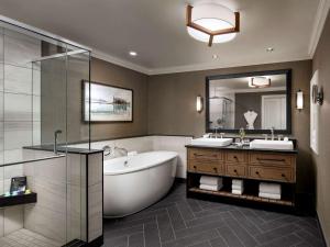 a bathroom with a tub, sink, mirror and bathtub at Fairmont Chateau Whistler in Whistler