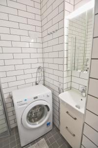 uma casa de banho branca com uma máquina de lavar roupa e um lavatório em HOMELY - City Apartment 50m2 em Helsinque