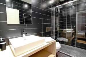 La salle de bains est pourvue de carrelage noir, d'un lavabo et de toilettes. dans l'établissement Appartements Urban et Pure, à Cannes