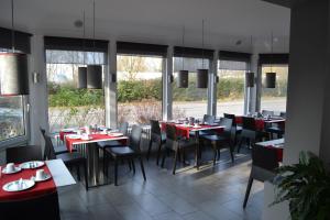 a restaurant with red tables and chairs and windows at Hotel Am Leinritt in Kahl am Main