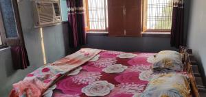 Bett in einem Zimmer mit einer rosa und weißen Decke in der Unterkunft Vishnu Rest House in Varanasi