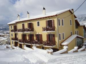 un edificio amarillo con nieve en el suelo en Ahilion Hotel, en Kalavrita