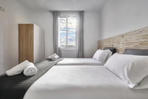 1 dormitorio con 2 camas, sábanas blancas y toallas en BBarcelona Fira Superior Flats en Barcelona