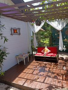 a patio with a red couch under a pergola at RECANTO DO SOL "Aluguel de quartos - Hospedagem Simples" in Ilha do Mel