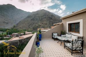 a balcony with a table and chairs and a mountain at Mount Toubkal Lodge in Imlil