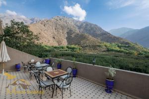 a patio with tables and chairs with mountains in the background at Mount Toubkal Lodge in Imlil
