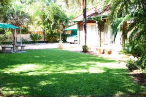 einen grünen Hof mit Bänken und einem Haus in der Unterkunft De la Rose Guesthouse in Lephalale