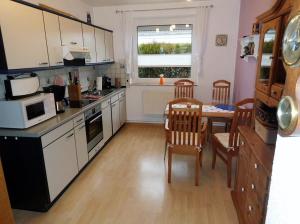 a kitchen with a table and chairs and a microwave at Kolks Huus Seglerweg in Neuharlingersiel