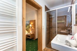a bathroom with a white sink and a shower at Landhotel Hinteraigengut in Flachau