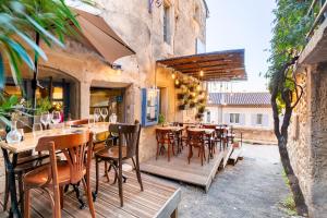 ein Restaurant mit Holztischen und -stühlen auf einer Terrasse in der Unterkunft Le Pied de la Lettre in Grignan