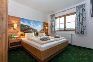 a bedroom with a large bed and a large window at Landhotel Hinteraigengut in Flachau