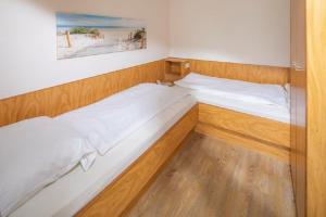 two twin beds in a room with wooden floors at Ferienwohnung Kogge 4 in Norderney