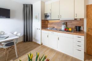 a kitchen with white cabinets and a table and a desk at Ferienwohnung Kogge 4 in Norderney