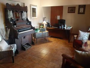 ein Wohnzimmer mit einem Klavier und einem Schreibtisch in der Unterkunft Acacia Gastehuis in Kathu