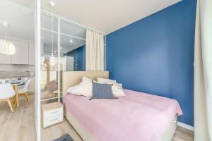 Un dormitorio con una cama y una pared azul. en Ustronie Apartments 20 m do plaży, en Ustronie Morskie 284 fotos más