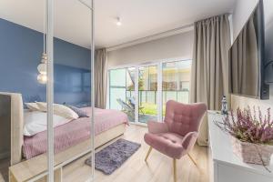 a bedroom with a pink bed and a chair at Ustronie Apartments 20 m do plaży in Ustronie Morskie