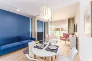 Ustronie Apartments 20 m do plaży في أوستروني مورسكي: غرفة معيشة مع أريكة زرقاء وطاولة وكراسي