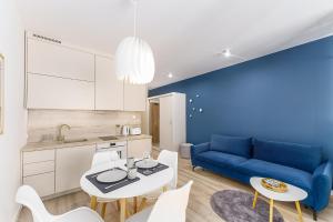 uma sala de estar com um sofá azul e uma mesa e cadeiras em Ustronie Apartments 20 m do plaży em Ustronie Morskie